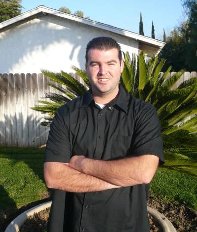 A man standing in front of a house with his arms crossed.